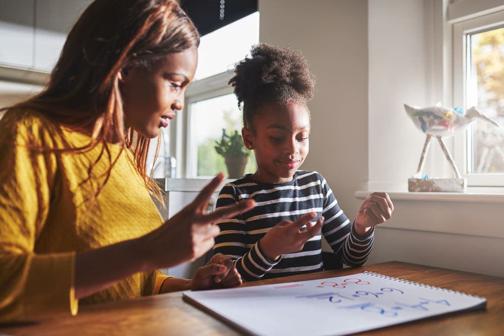 A parent helping her daughter with a learning exercise at home