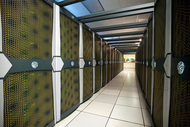 Two long rows of supercomputer cabinets stretching down a cooled computer hall.