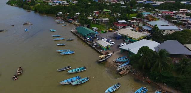 An aerial view of the fishing port at Otaheite Bay, Trinidad: small boats moored in the river beside the fish market building and the town.