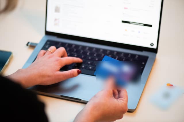 A shopper types card details into a laptop to pay for goods online.