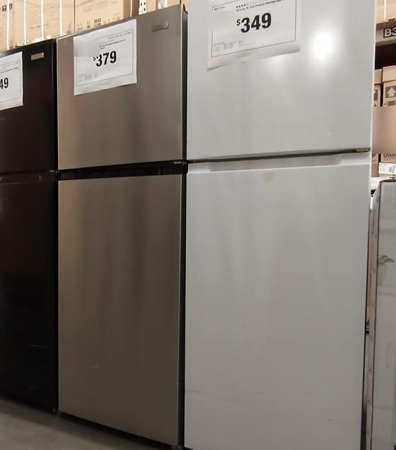 A row of refrigerators in a store, each with a large price card such as $349 and $379.